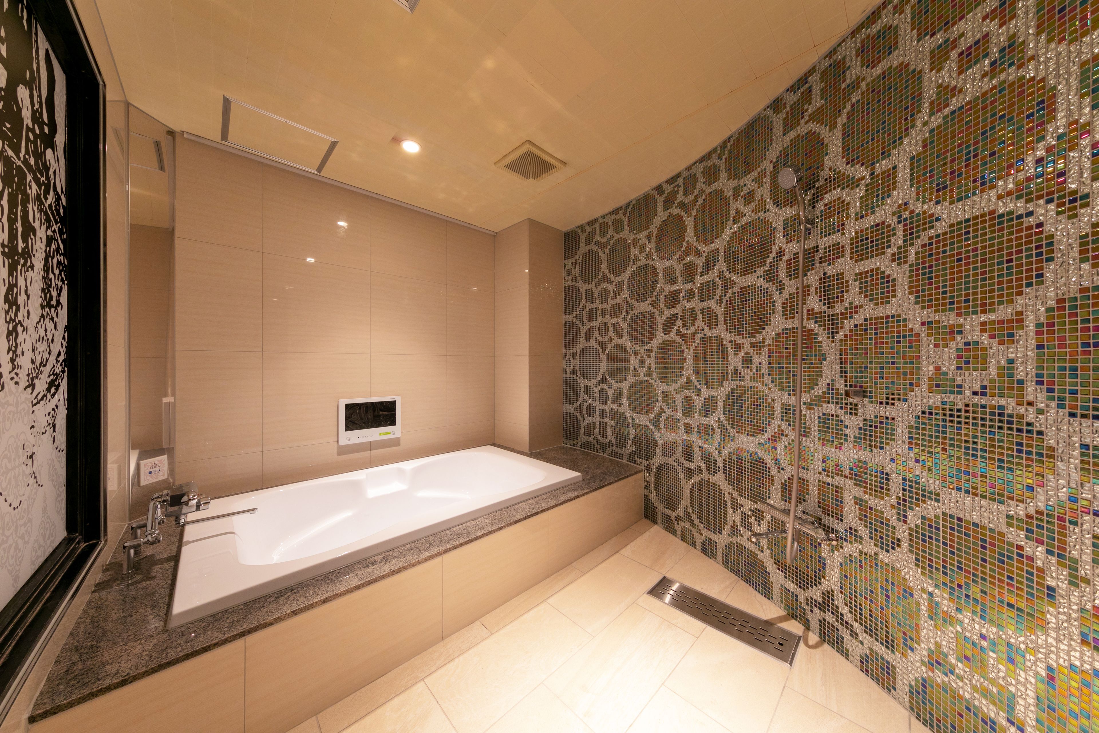 Un baño moderno con una bañera grande, ducha y pared de mosaicos.