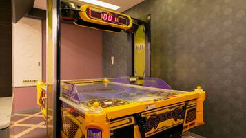 A pinball machine in a room with a hexagonal patterned wall and a door in the background.