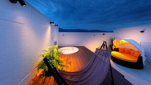 A rooftop terrace with a hot tub, a hammock, and a canopy bed.