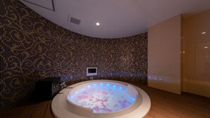 A modern bathroom with a freestanding bathtub, a tiled wall with a floral pattern, and a wooden floor.