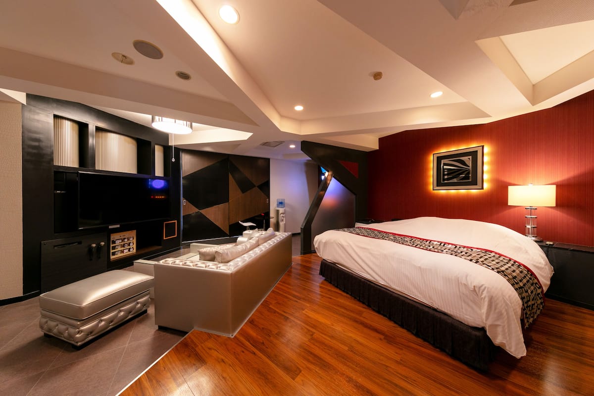 Une chambre d’hôtel moderne dotée d’un grand lit, d’une télévision à écran plat, d’un coin salon et d’un mini-bar.