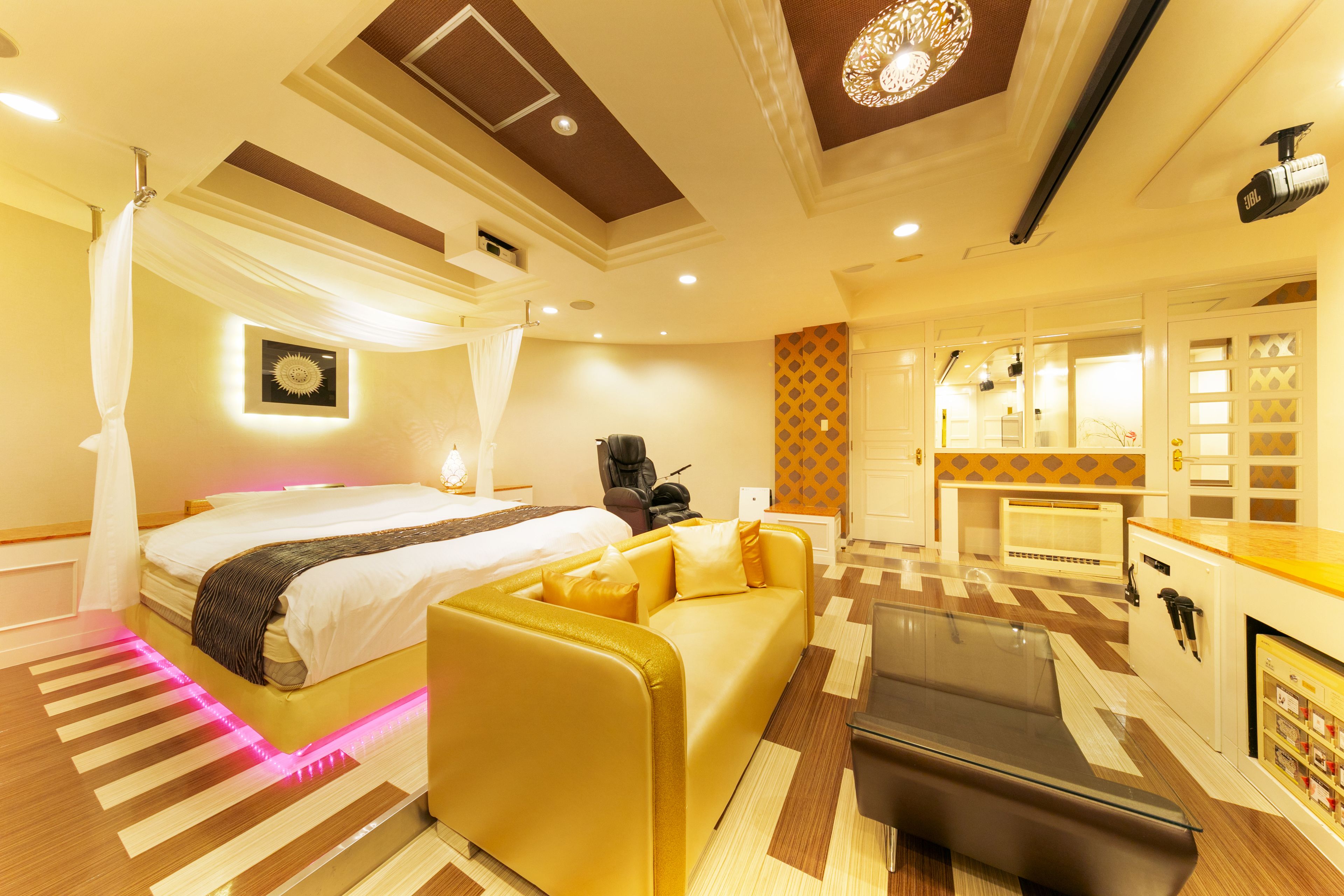 Una habitación de hotel con cama, sofá, mesa de centro y minibar.
