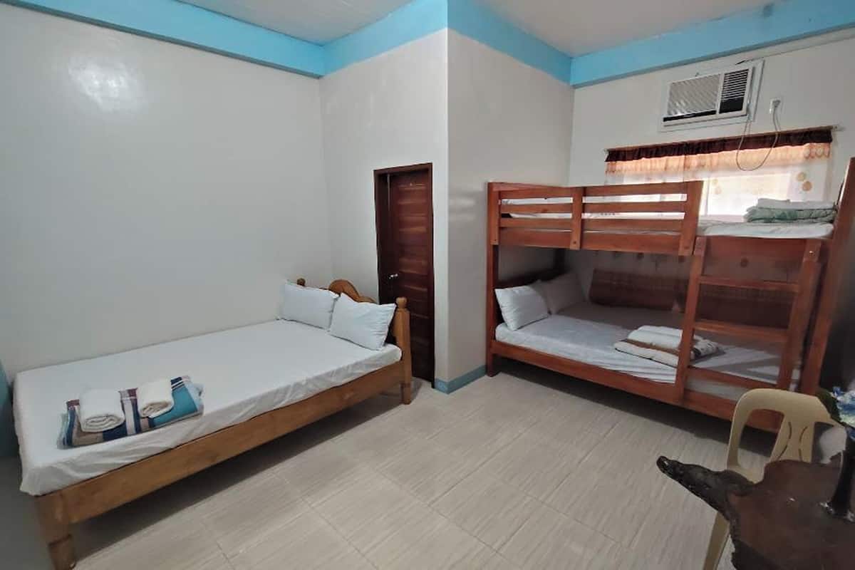A room with two wooden bunk beds, a single bed, and a chair.