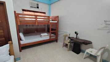 A dormitory room with bunk beds, a desk, a chair, and a radiator.