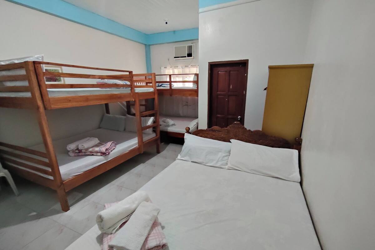 A room with bunk beds, a single bed, a chair, and a door.