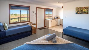 A compact room with two beds, a small kitchenette, and a view of the outdoors. - Cheela Plains Station (Nanutarra)