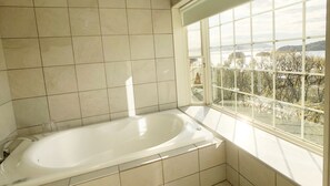 A bathroom with a bathtub, tiled walls, and a window with a view of trees and hills. - La Krasse Angelroad (Tonosho)
