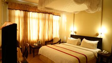 Habitación de hotel con una cama grande, una silla, una mesita pequeña y una mesita de noche con un teléfono.