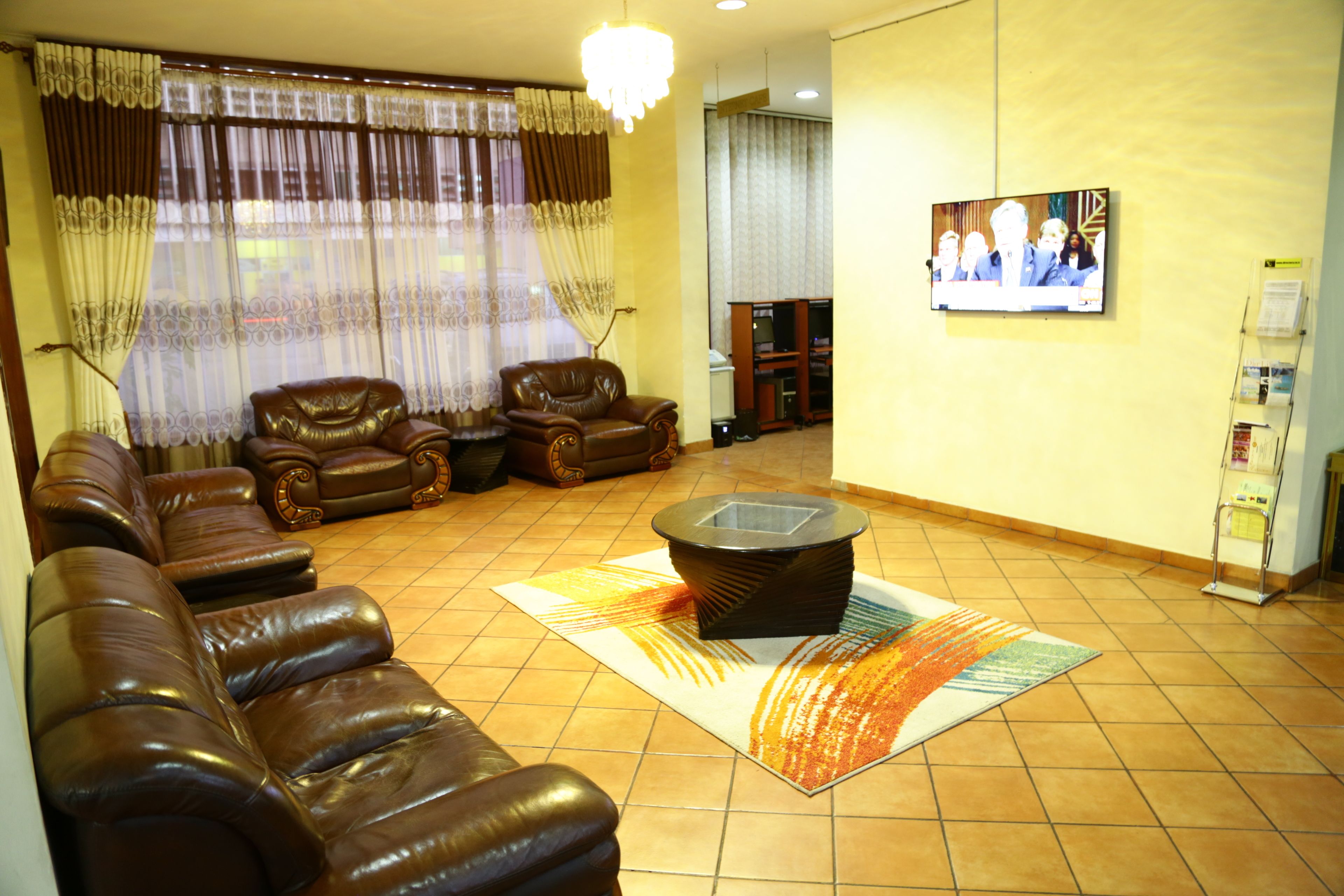 Una sala de estar con sofás de cuero, una mesa de centro y un televisor montado en la pared.