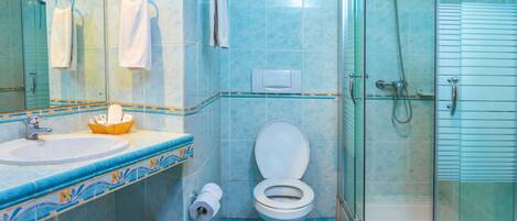A bathroom with a glass-enclosed shower, a sink with a basket, and a toilet.
