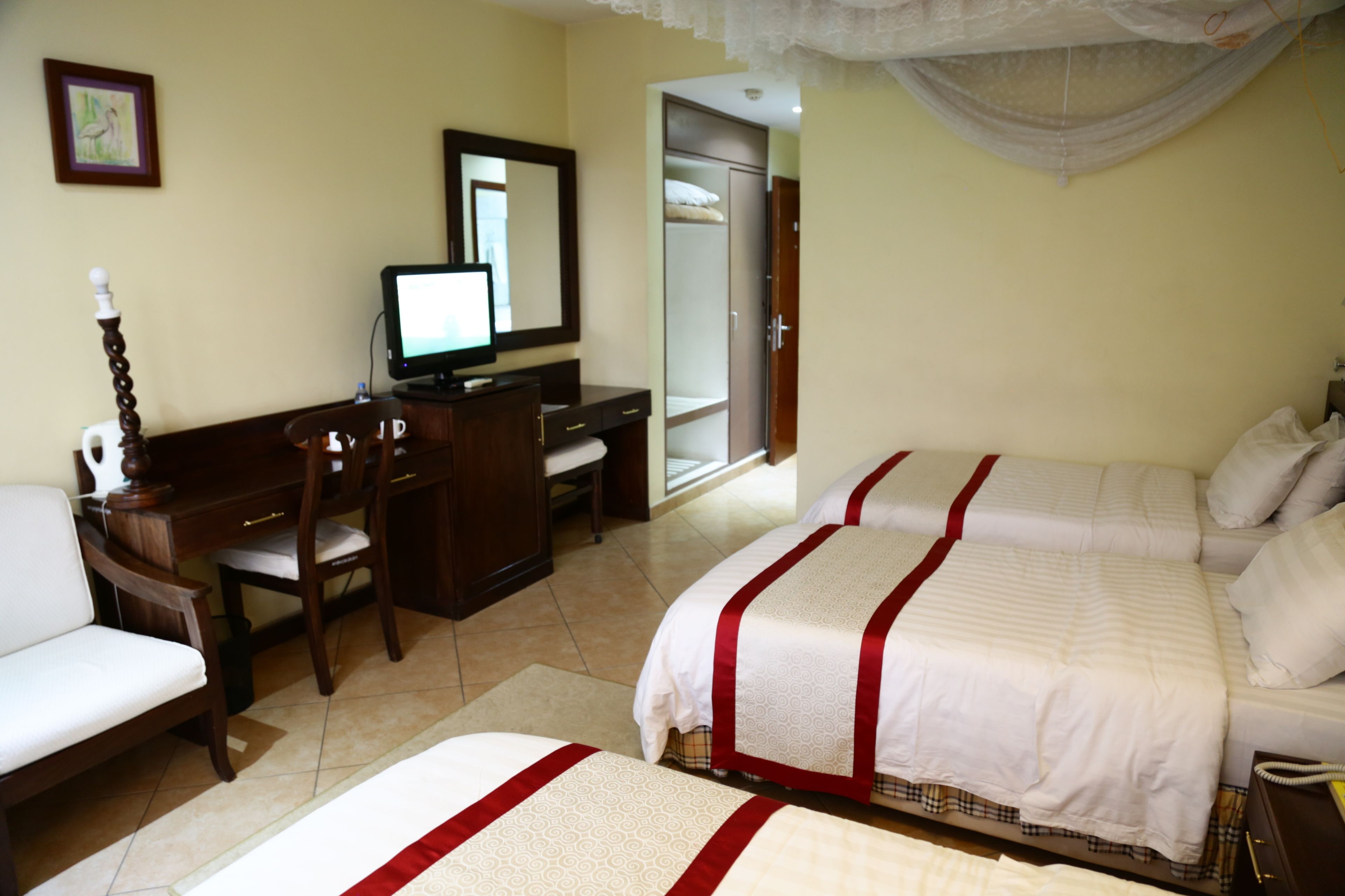 A hotel room with two beds, a desk with a computer, a chair, and a wardrobe.