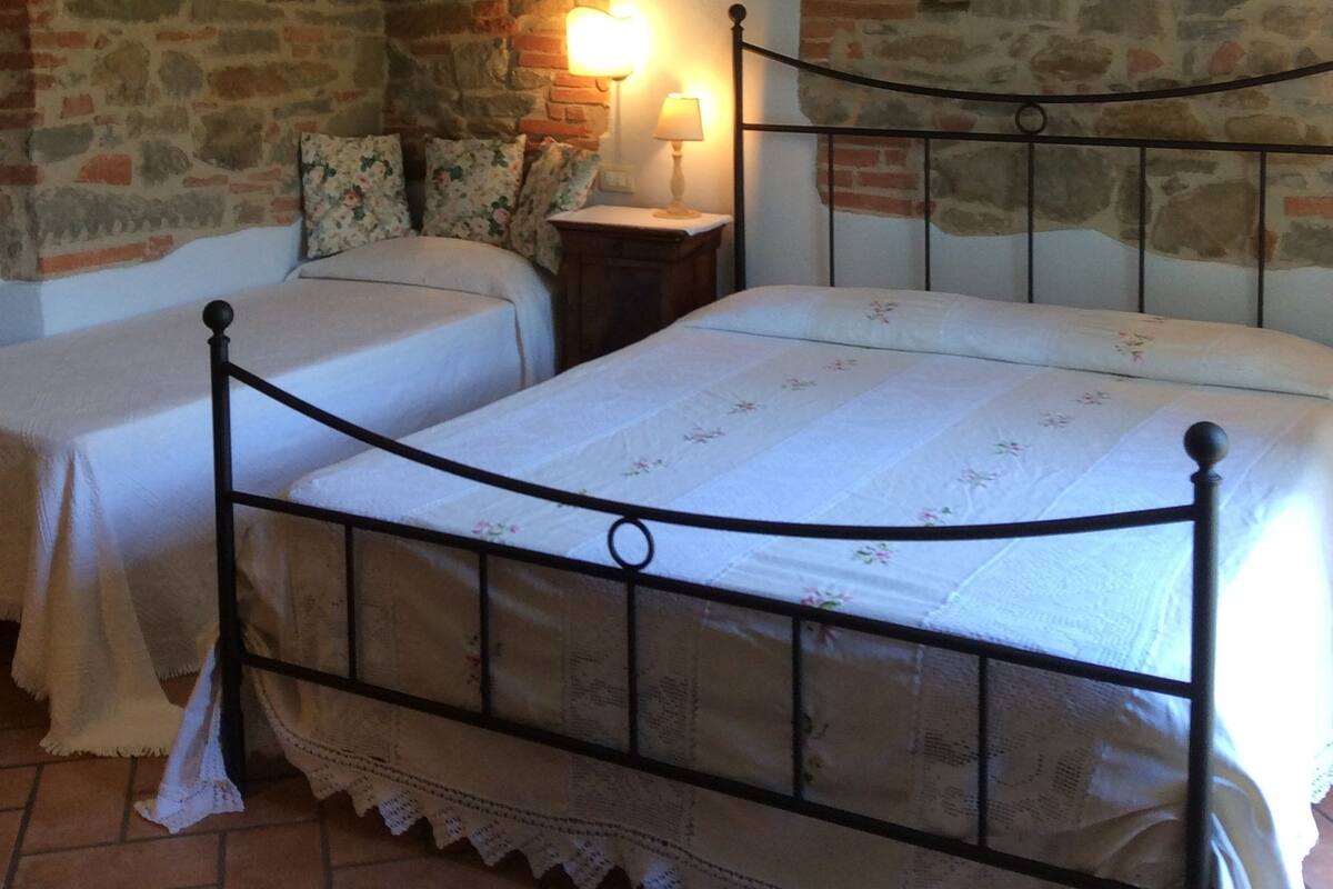 Ein Schlafzimmer mit Stewand, einem Bett mit Metallgestell und einem Nachttisch mit Lampe.