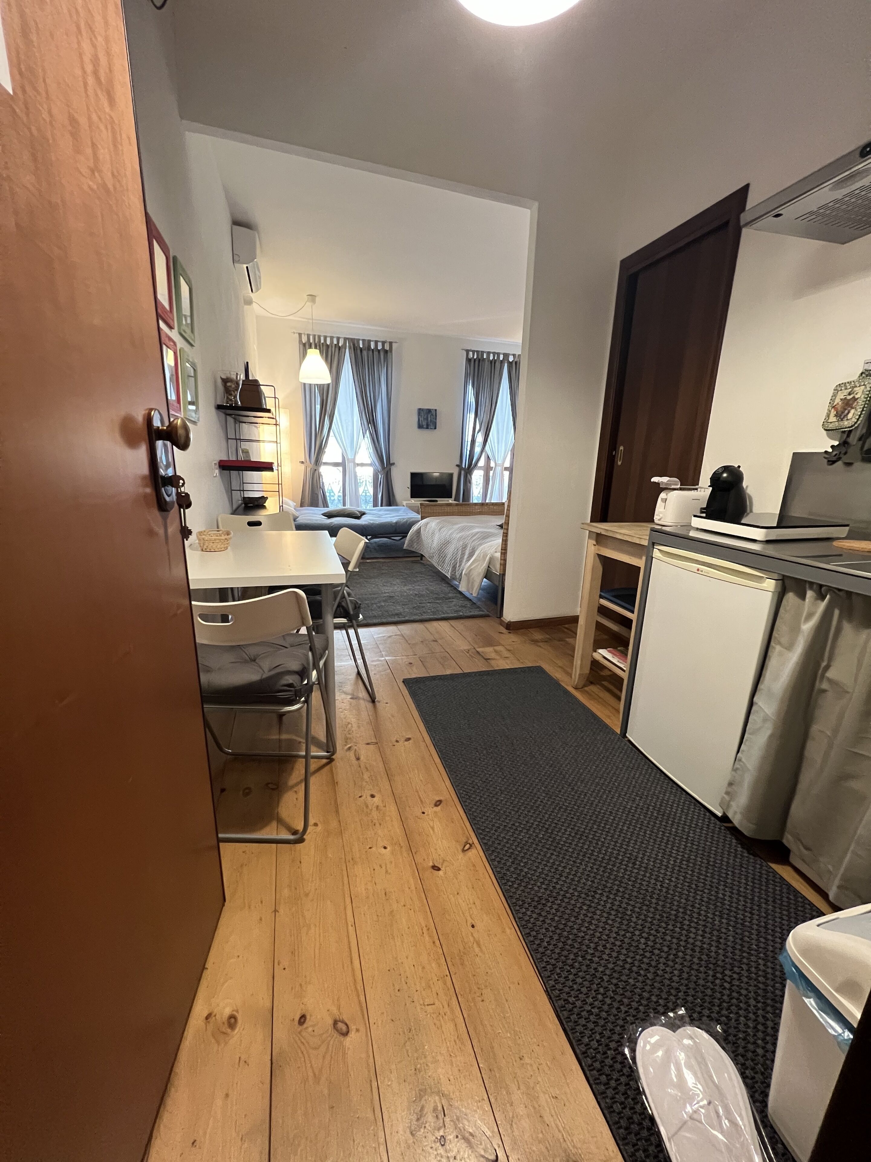 Una habitación de hotel pequeña con kitchenette, comedor y cama.
