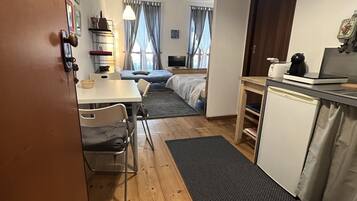 Una habitación de hotel pequeña con kitchenette, comedor y cama.
