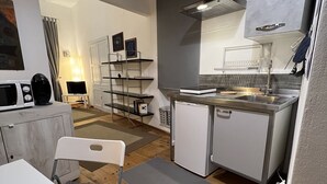 Een kleine keuken met een eethoek, een kleine koelkast en een magnetron.