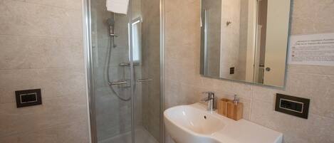 A modern bathroom with a glass-enclosed shower, a white sink, and a mirror above it.