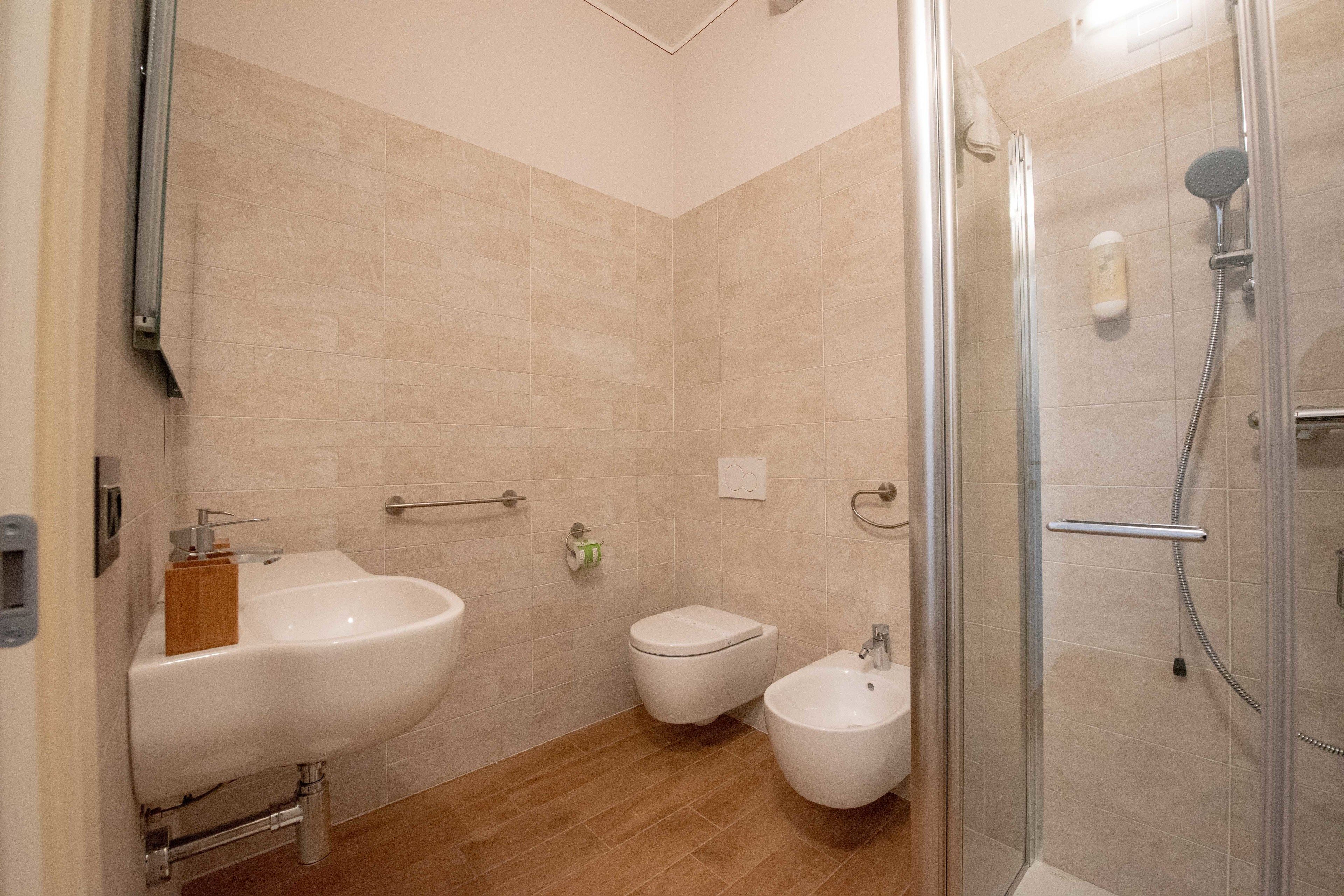 Un baño moderno con lavamanos, inodoro, bidé y cabina de ducha de vidrio.