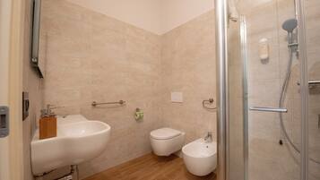 Un baño moderno con lavamanos, inodoro, bidé y cabina de ducha de vidrio.
