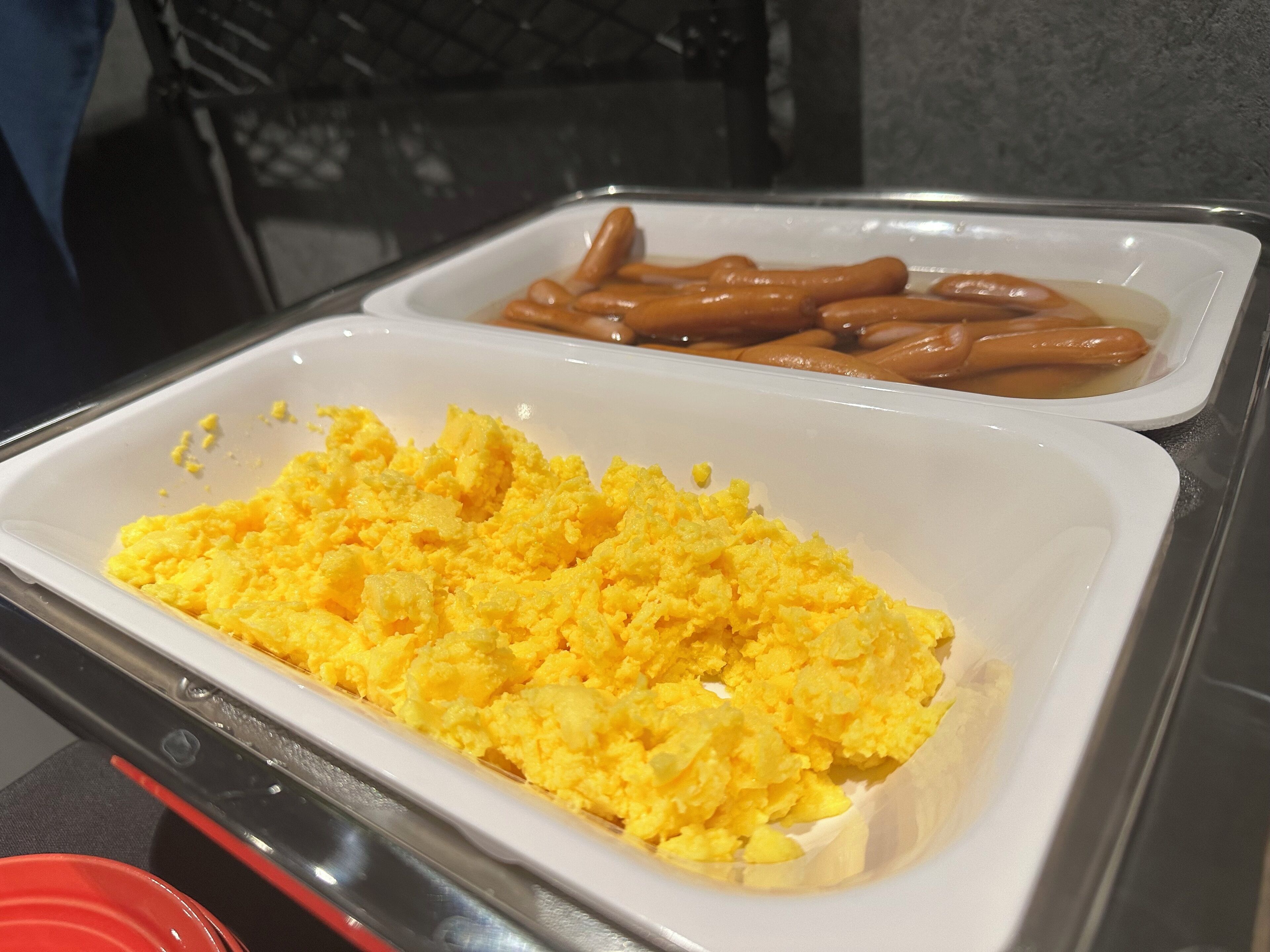 A buffet with scrambled eggs and sausages.
