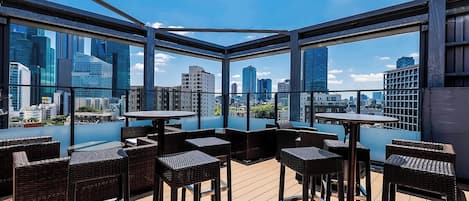 Terraza en la azotea con mobiliario de mimbre y vistas a la ciudad.