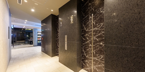 A modern hallway with dark marble walls and a tiled floor, leading to a glass door entrance. - HOTEL SUI AKASAKA byABEST (Tokyo)