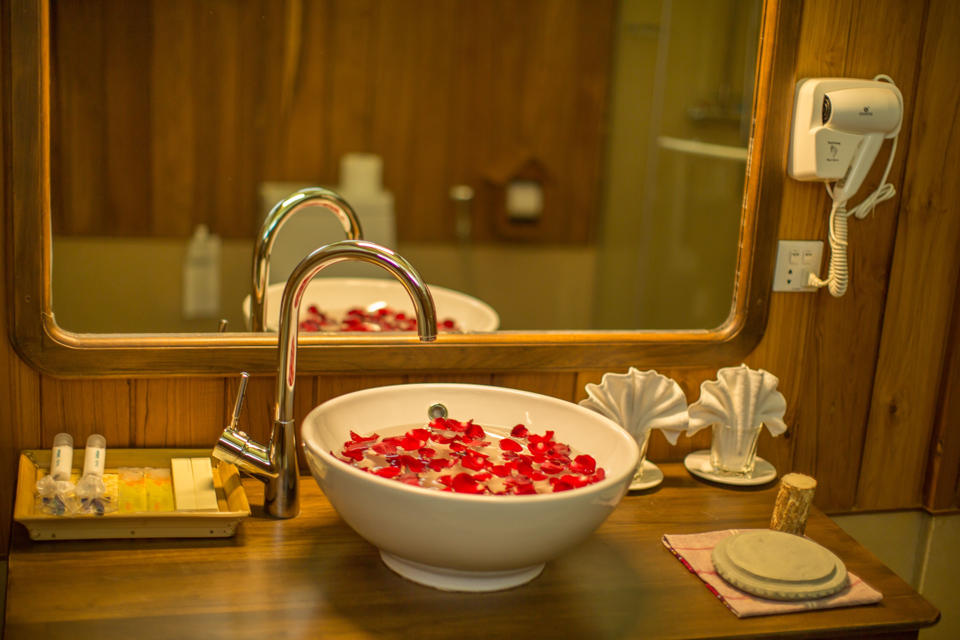 A bathroom with a white sink, a mirror, a hairdryer, and toiletries on the counter.