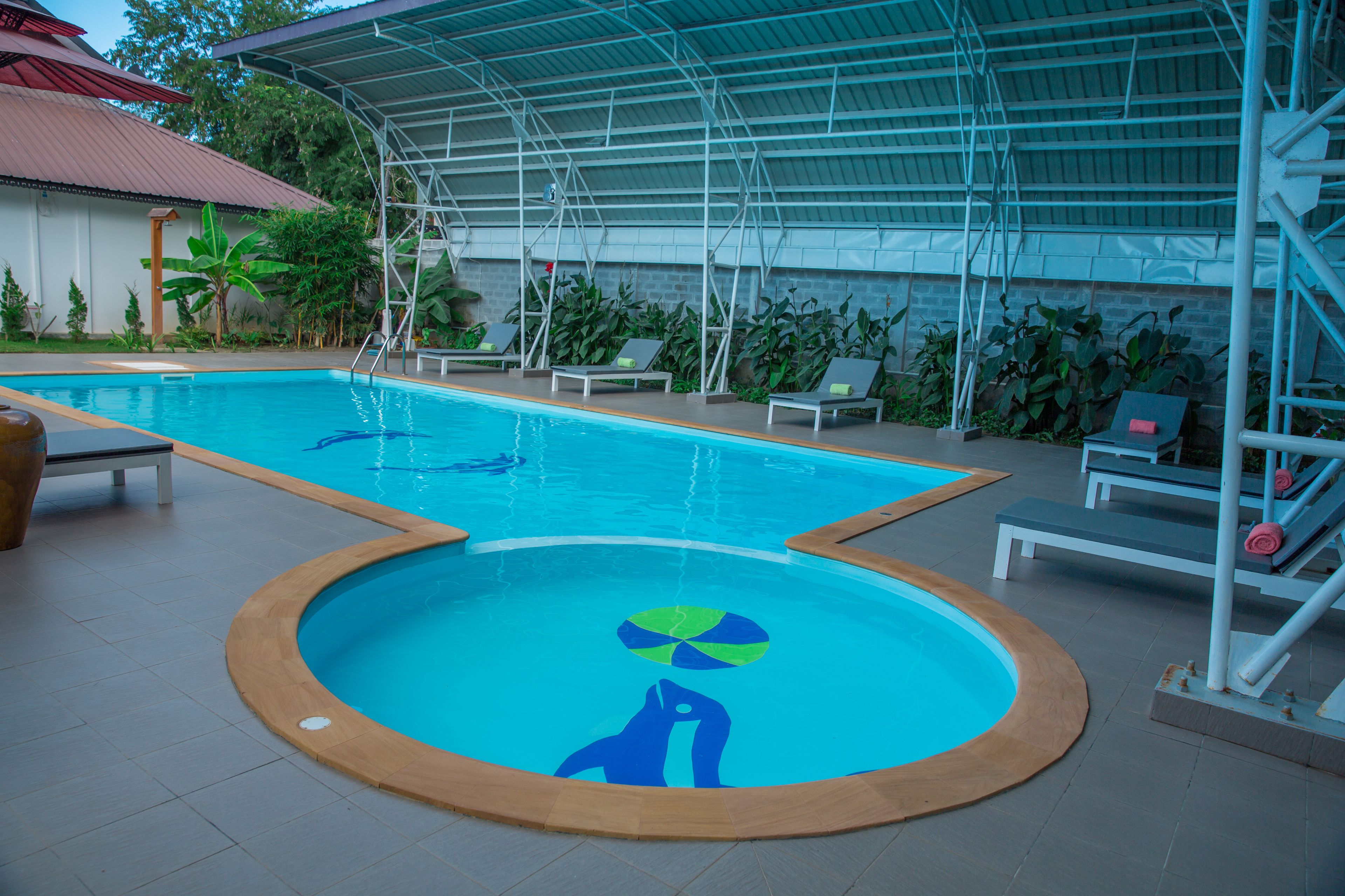 A swimming pool with a covered area, lounge chairs, and a lifeguard stand.