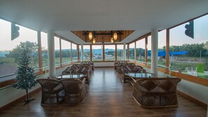 A spacious indoor area with wicker furniture and large windows offering a view of the outdoors. - Spring Lodge Inle (Nyaungshwe)