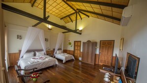 A hotel room with two beds, a wooden floor, a dining area, and a television. - Spring Lodge Inle (Nyaungshwe)