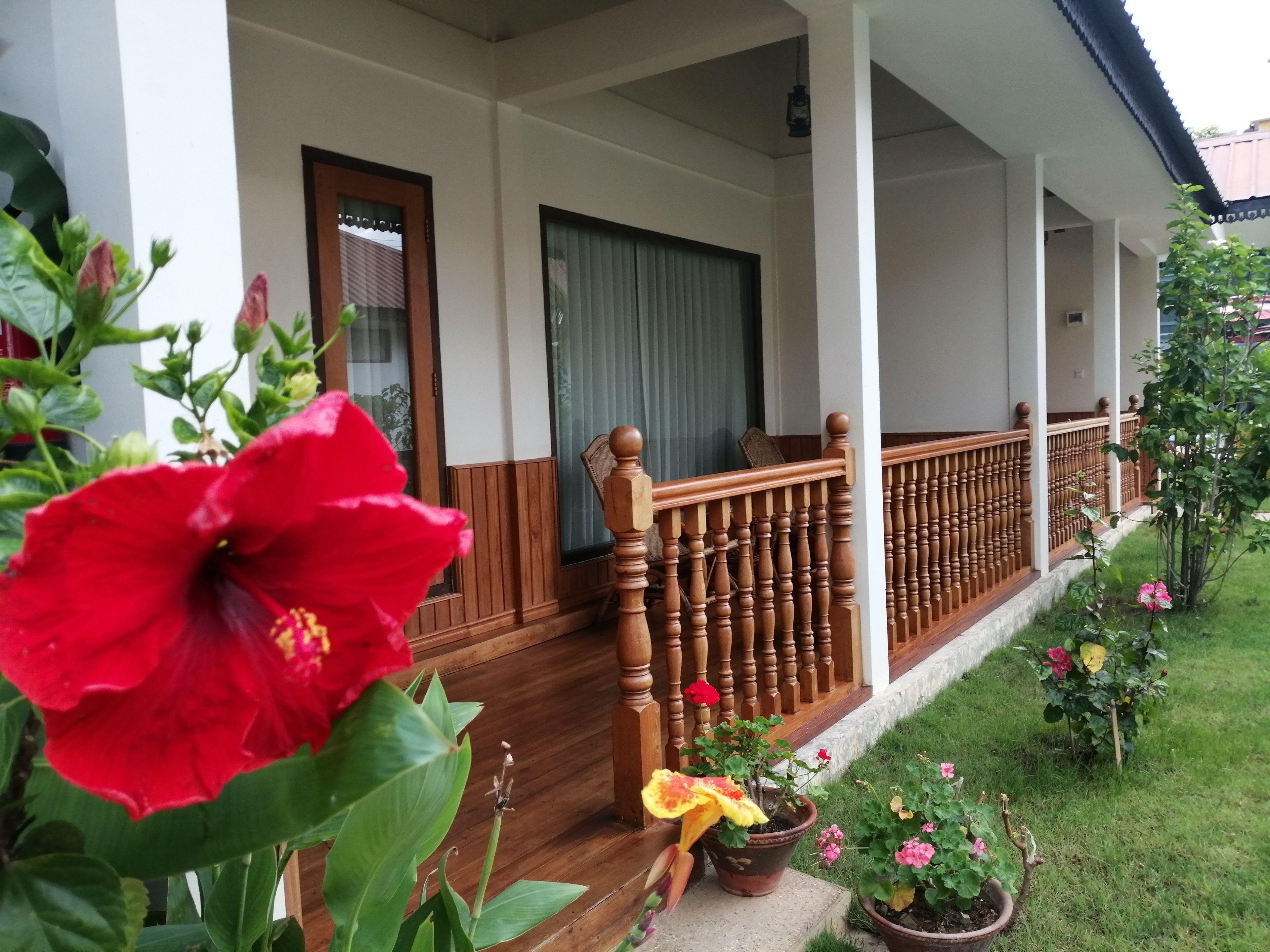 A covered porch with wooden railings and potted plants.