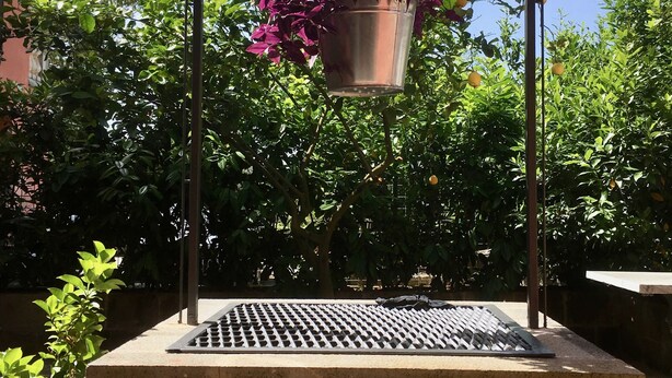 A hanging planter with purple flowers, a metal grill, and a stone base. - Residenza Viviani (Sant'Agnello)