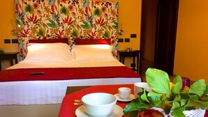 A hotel room with a bed, a dining table with a red tablecloth, a plant, and a red candle. - Residenza Viviani (Sant'Agnello)