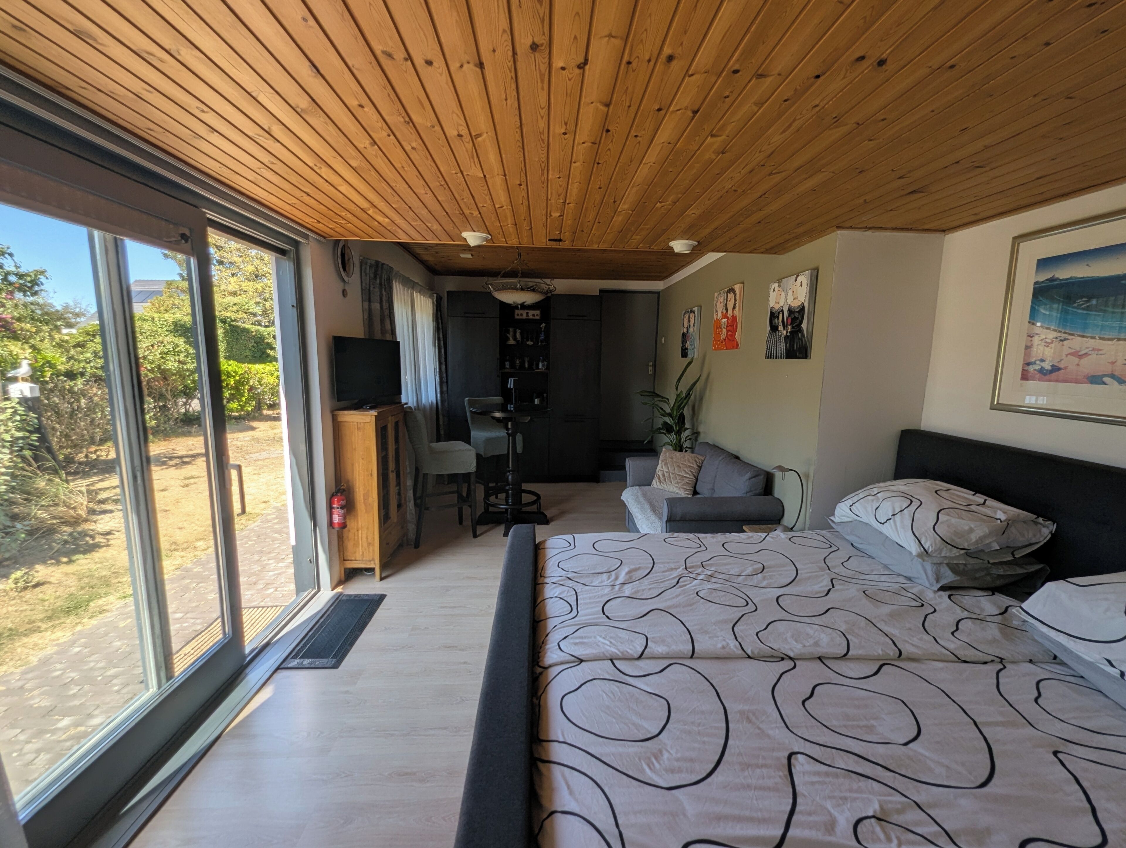 Un dormitorio con una cama grande, un sofá, un televisor y vistas al exterior.