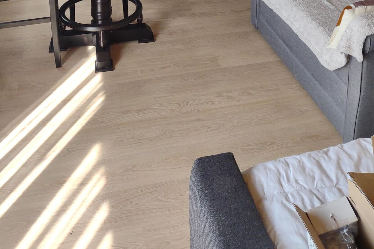 Un salon moderne comprenant un canapé, une table à manger avec des chaises et un coin cuisine avec des placards et un luminaire suspendu.