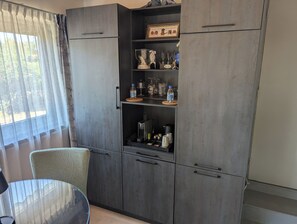 Une cuisine moderne avec des meubles de rangement aux couleurs foncées, une table en verre et une chaise de salle à manger.