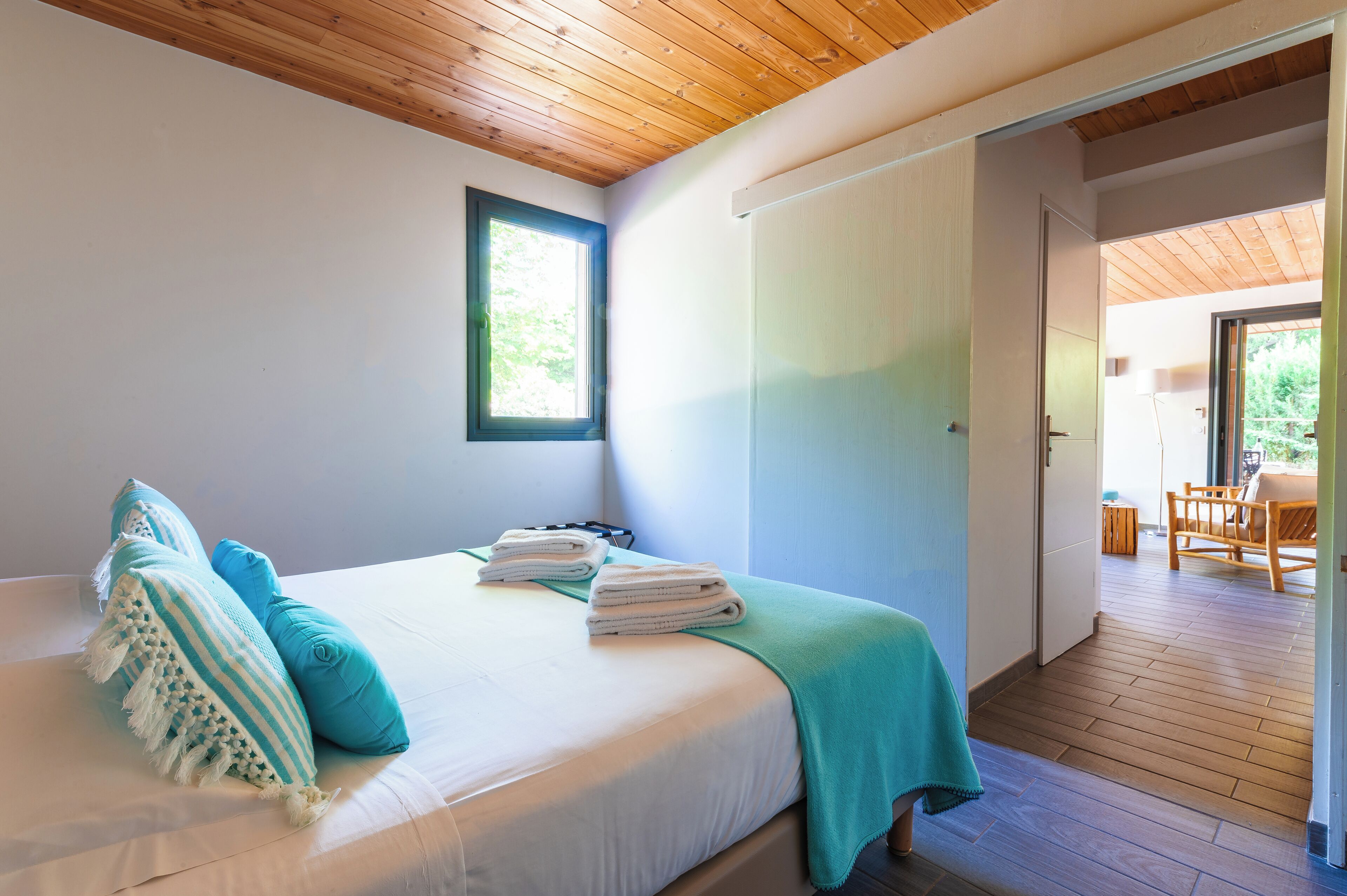 Un dormitorio con cama, almohadas, ventana y puerta que da a un balcón.