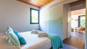 Un dormitorio con cama, almohadas, ventana y puerta que da a un balcón.