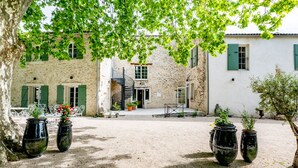 A courtyard with stone buildings, a spiral staircase, and potted plants. - Domaine des Tilleuls (Malaucene)