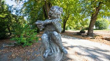 Eine Steinstatue einer Figur, die ein Kind in einer Parkanlage hält.
