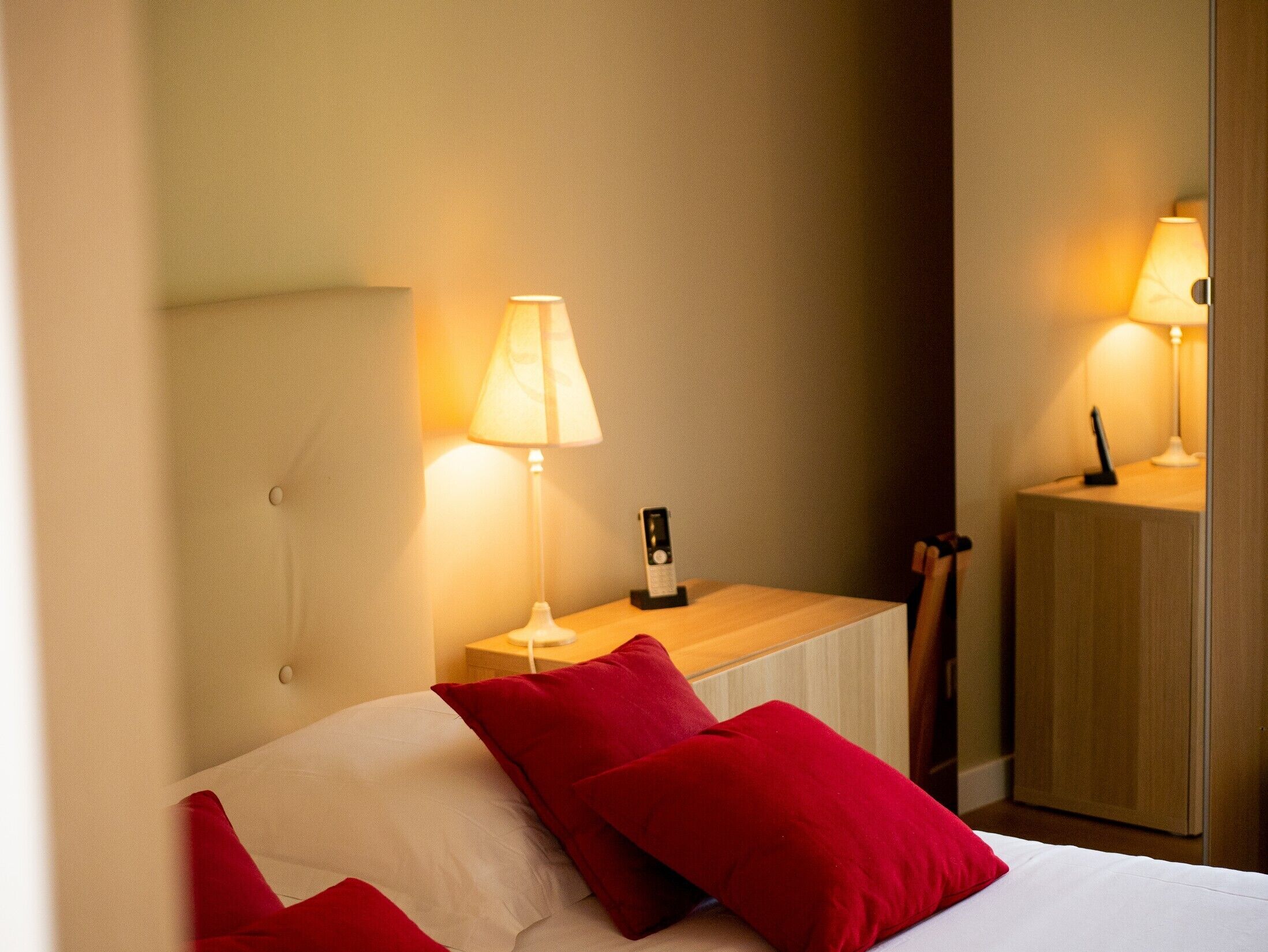 Une chambre d’hôtel avec un lit, deux lampes de chevet et une table de chevet équipée d’un téléphone et d’une lampe.