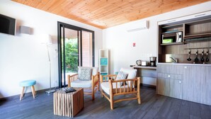 A modern kitchen with wooden cabinets and a built-in microwave. There is a seating area with two wooden chairs and a small table. - Domaine des Tilleuls (Malaucene)