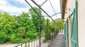 A balcony with a metal railing overlooking a lush green garden. - Domaine des Tilleuls (Malaucene)