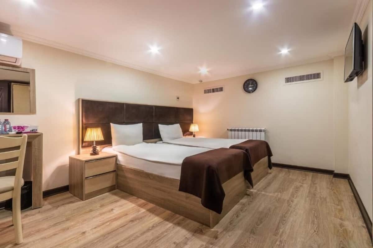 Una camera d'albergo con un letto grande, comodini, una scrivania e una televisione.