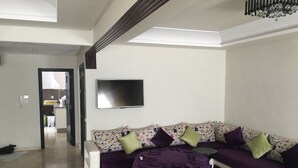 Una sala de estar con un sofá, una mesa de centro y un televisor montado en la pared.