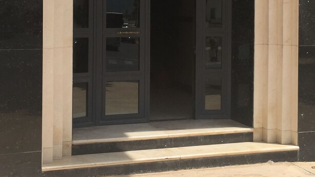 Entrada de un edificio con una puerta oscura y un marco claro.