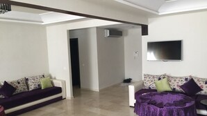 Una sala de estar con dos sofás, una mesa de centro y un televisor de pantalla plana montado en la pared.