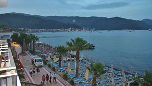 A coastal hotel with a promenade, beach umbrellas, and a marina with boats. - George Dragon Beach Hotel (Marmaris)