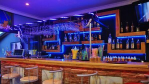 A bar area with multiple shelves of bottles, a bar counter, and several bar stools. - George Dragon Beach Hotel (Marmaris)