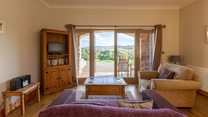 A living room with a wooden cabinet, a television, a sofa, and a table. - Kennacoil (Dunkeld)