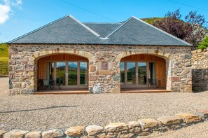A stone building with two large arched windows and a gravel driveway. - Kennacoil (Dunkeld)